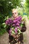 Senior pensioner woman cut lilac bush with secateurs