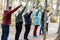 Senior people with female coach leader hold Nordic trekking sticks in air while hiking in the forest. Exercise education
