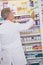 Senior pharmacist taking box from shelf