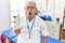 Senior physiotherapy man holding massage body lotion scared and amazed with open mouth for surprise, disbelief face