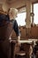 Senior potter in apron standing and leaning on table at workshop