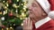 senior praying sitting by christmas tree at home