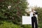 Senior real estate agent standing by sign board reading from clipboard