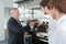 Senior restaurant owner next to coffee bar with workers