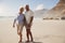 Senior Retired Couple Walking Along Beach Hand In Hand Together