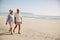 Senior Retired Couple Walking Along Beach Hand In Hand Together