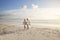 Senior Retired Couple Walking Along Beach Hand In Hand Together