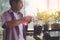 Senior retired man is spraying water on plant pot in morning light