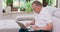 A senior retired man types on a laptop computer at home on a couch Elderly grandfather wearing eyeglasses and working on