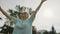 Senior retired woman dancing in the park with outstretched hands low angle shot