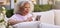 Senior Retired Woman Sitting Outside In Garden At Home Making Video Call On Mobile Phone