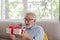 Senior retirement man is happy with his surprise birthday gift on sofa