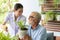 Senior retirement man and nurse are watering a small plant while relax at home
