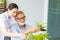 Senior retirement man and nurse are watering small plant while relax at home
