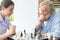 Senior retirement man playing chess with nurse at home