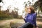 Senior runner sitting on wooden logs, resting, drinking water.