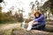 Senior runner sitting on wooden logs, stretching, drinking water