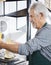 Senior Salesman Packing Cheese At Grocery Store