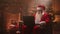 Senior Santa Claus with a white beard is sitting in a chair and is engaged in Internet banking. view their accounts and