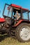 senior self-employed farmer in straw hat driving tractor.