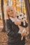 Senior smiling woman hugging her dog in autumn park. Active aging and pet concept.