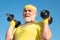 Senior sport man exercising with dumbbell. Be in motion. Grandfather sportsman portrait on blue sky backgrounds. Sport
