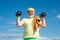Senior sportman exercising with lifting dumbbell on blue sky background. Isolated, copy space.