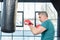 Senior sportsman in red boxing gloves punching bag