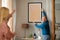 Senior Spouses Hanging Poster In Frame On Wall Decorating Home