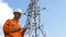 Senior surveyor puts data in smartphone by power lines tower