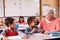 Senior teacher sitting with elementary school kids in class