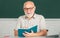 Senior teacher teaching in the classroom on chalkboard. Teacher at university. Teacher in glasses and book. Bearded