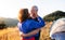 Senior tourist couple in love standing in nature at sunset, hugging.