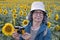 Senior tourist using vintage camera in sunflowers field