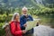 Senior tourists with backpacks reading map, preparing for hike.