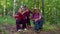 Senior tourists grandmother, grandfather, granddaughter kid talking, sitting with backpacks in wood