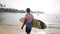 Senior traveler surfer holds surf board and walking at exotic beach on tropical island. Black old bearded man in