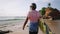 Senior traveler surfer holds surf board and walking at exotic beach on tropical island. Black old bearded man in