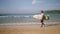 Senior traveler surfer holds surf board and walking at exotic beach on tropical island. Black old bearded man in