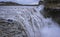 Senior travelers contemplating Detifoss waterfall on the edge in Iceland.