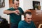 Senior twin cutting his brother`s hair at home during coronavirus lockdown - Focus on right man
