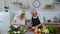 Senior vegan grandmother and grandfather cooking salad with fresh vegetables in kitchen at home