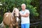 Senior veterinarian with palomino horse on sunny day