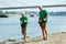 Senior volunteers gathering garbage on river bank.