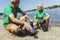 Senior volunteers gathering garbage on river bank.