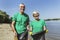 Senior volunteers gathering garbage on river bank.