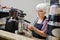 Senior Waitress Steaming Milk In Cafe