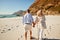 Senior white couple walking on a beach holding hands, back view, three quarter length, close up
