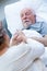 Senior wife giving glass of water to her sick husband