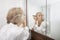 Senior woman applying eyeliner while looking at mirror in bathroom